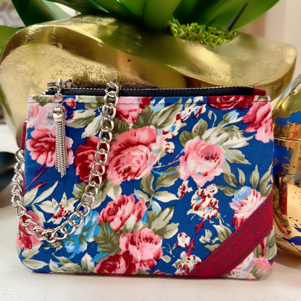 Floral patterned handbag with a chain strap on a white surface